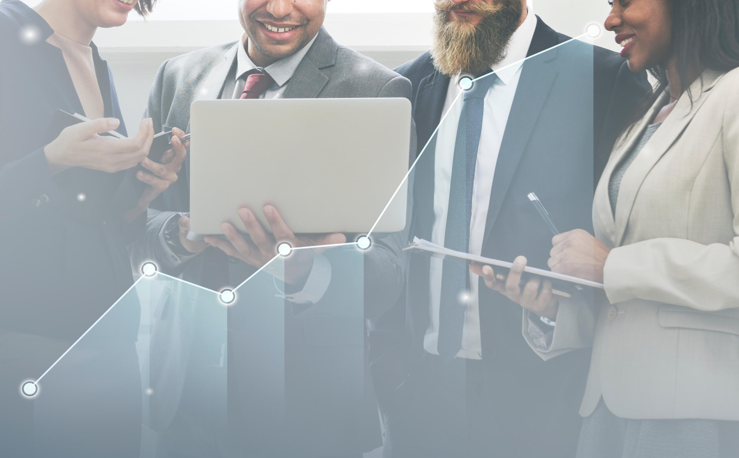 Group of business workers in suits standing together looking at a laptop with smiles, with a line graph trending upwards that overlays the picture